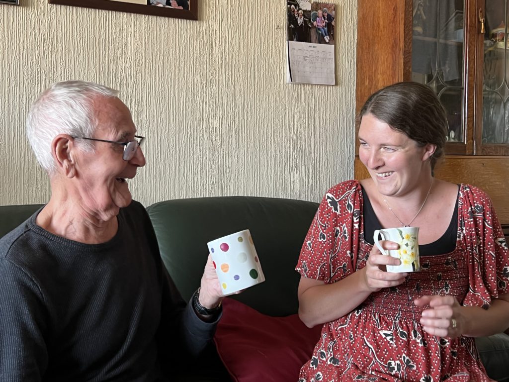 carer and elderly gent having a cup of tea and a happy chat